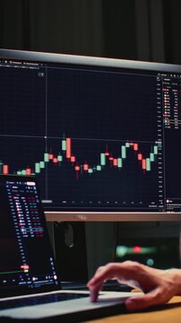 Man trader monitors market charts on laptop, screen and smartphone at home. Analyzing real-time trading data, considering investment strategies. Professional investor engaged in day trading, Evening