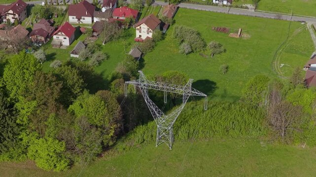 Top down view of high tension electricity pylon and lines crossing Simon village valley, slow forward medium telephoto, graded 4K