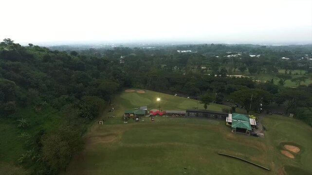 Aerial view of a scenic golf course and driving range surrounded by lush tropical greenery.