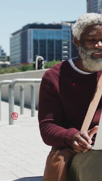 Vertical video: Man typing with laptop on bench, red symbols appearing and causing laugh for work