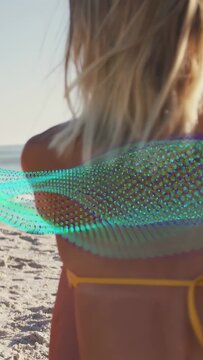 Vertical video: Teal ribbon sweeping across body, woman turning, brushing hair on beach for travel