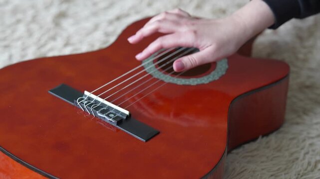 Close-up of female hand plucking guitar strings during performance.