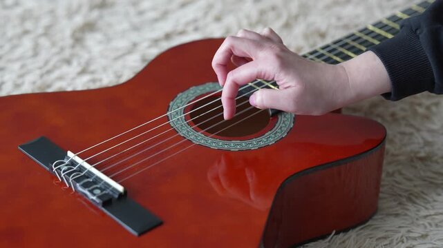 Close-up of female hand plucking guitar strings during performance.