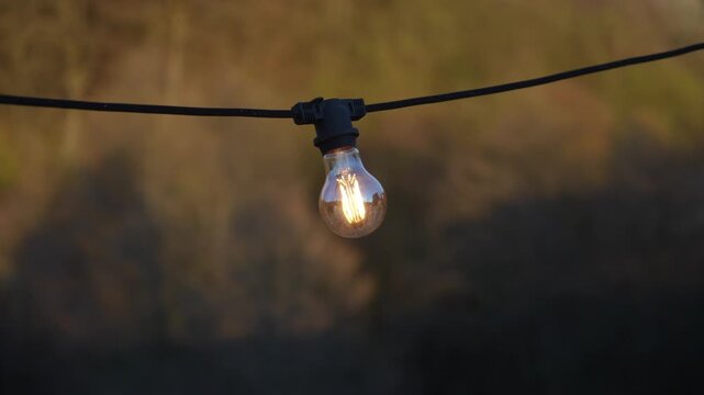 Close-up of glowing outdoor string light bulb creating warm atmospheric illumination.