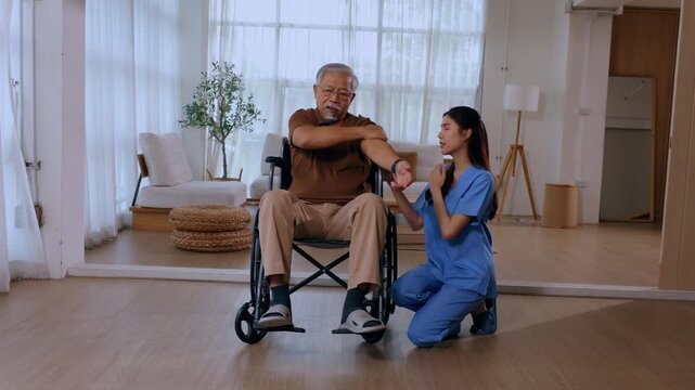 Caring Female Nurse Helping Focused Senior Man In Wheelchair With Physical Therapy Arm Exercise For Hopeful Indoor Recovery