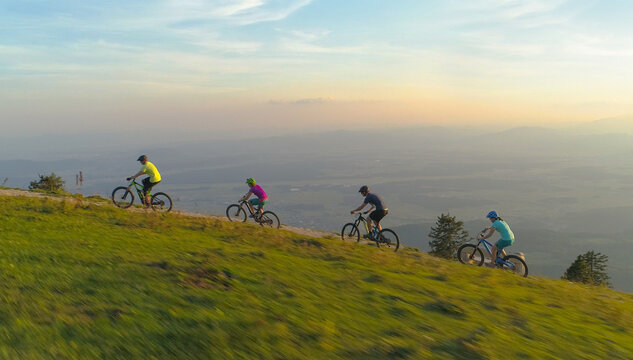 AERIAL: Scenic shot of friends riding mountain bikes uphill on a sunny morning.