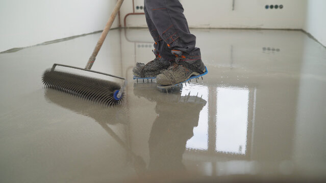 Worker applying self leveling epoxy floor coating with spiked roller