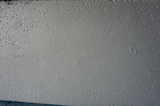 Macro shot of a white expanded polystyrene foam surface, showing the detailed cellular texture and structure. White plastic foam packaging material close-up.