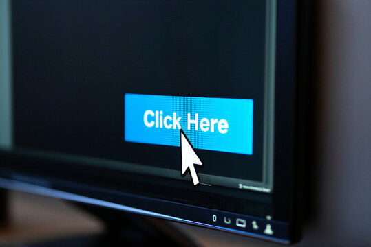 Closeup of a computer monitor displaying a blue click here button