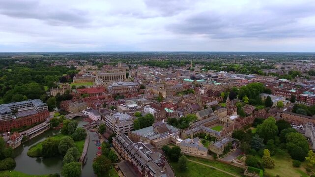 4K aerial wide panorama of Cambridge town with King's College Chapel, historic colleges, River Cam and punts under dramatic cloudy sky extending to Cambridgeshire fens horizon.