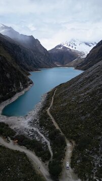 Huaraz, Peru: Aerial vertical drone footage of famous laguna paron in Caraz, Huaraz region, Peru, in Andes mountain with Piramide peak in cordillera blanca. Taken with forward and tilt up motion