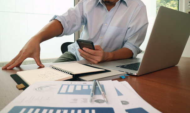 Businessman Using Smartphone With Laptop And Documents
