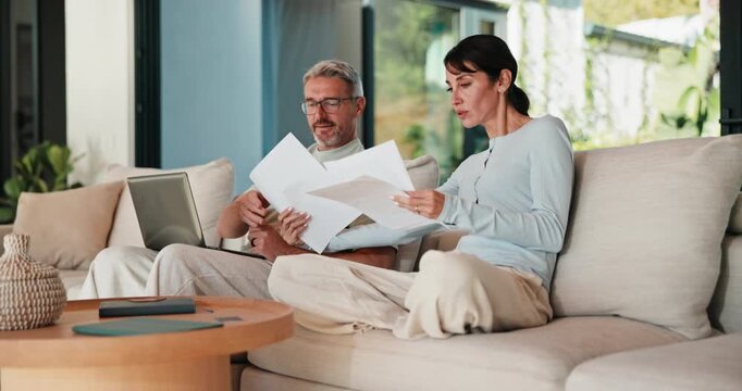 Couple, laptop and reading with documents on sofa for finance, bills or investment in home. Mature man, woman or paperwork with tech for financial planning, budget expenses or invoices together