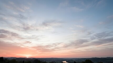 Obraz premium Beautiful panoramic sunset view over calm river winding through countryside hills and rural fields during dusk under colorful sky with scattered clouds.