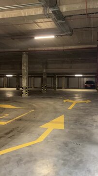 Empty underground parking garage with yellow directional arrows and concrete pillars, urban infrastructure, vehicle storage, transport navigation, modern facility.