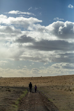 A man and 7 year old girl walking down a dirt road.