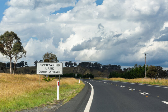Overtaking lane 300m ahead sign on road with dotted dividing line markings in rural Australia