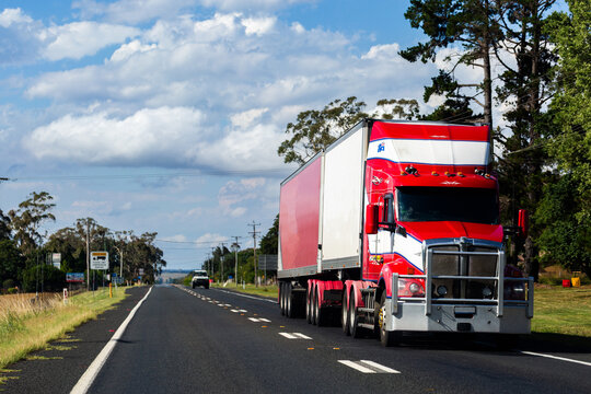 Red and white truck transporting goods on highway road near country town NSW