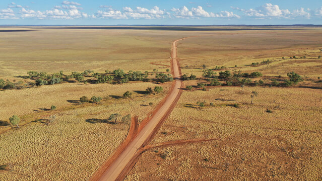 Drone shot of a dirt road going through creek and plain