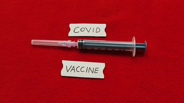 Coronavirus or covid contagious viral disease infection prevention and protection immunity booster vaccination or mrna injection concept. Hand placing syringe near covid vaccine word or text.