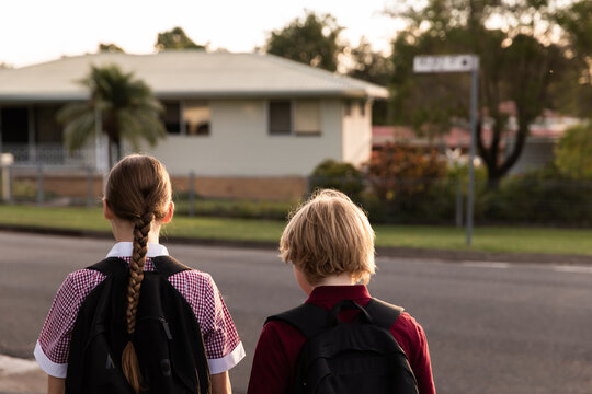 kids in school uniform walking with a suburban street in the background