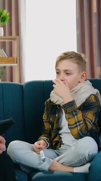 Close up of good-looking experienced friendly bearded pediatrician which asking about health well-being of ill exhausted sad teen boy during home visit ,then talking with boy's mother to clarify the