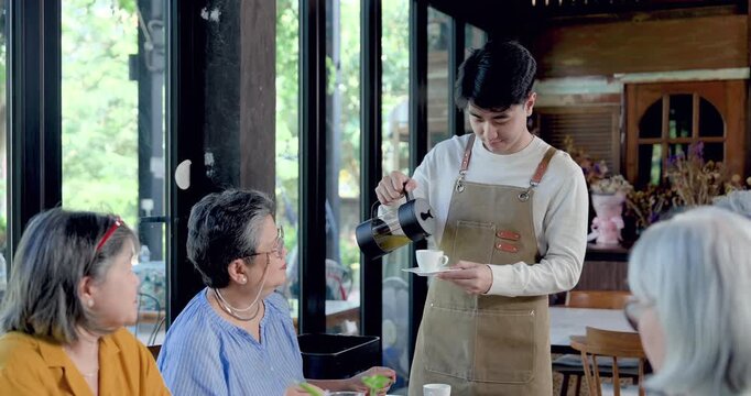 Senior Asian women friends reunion at restaurant table, retired female group receiving drink from waiter, sharing relaxed conversation, brunch service, companionship, togetherness, dining lifestyle