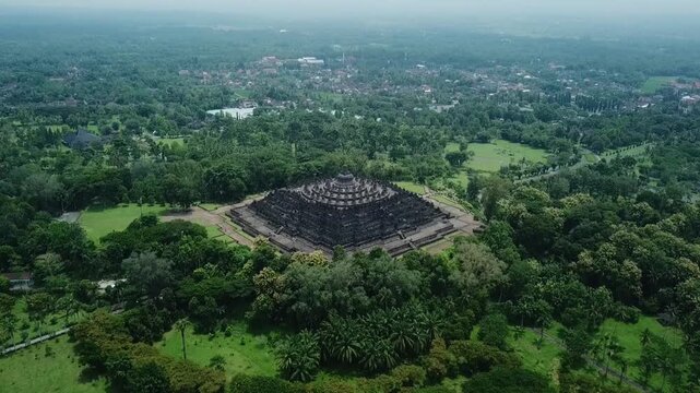 Aerial view of Borobudur Temple surrounded by lush green trees.