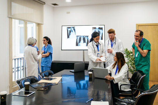 Diverse medical professionals discussing patient x rays and healthcare strategies in a modern hospital conference room