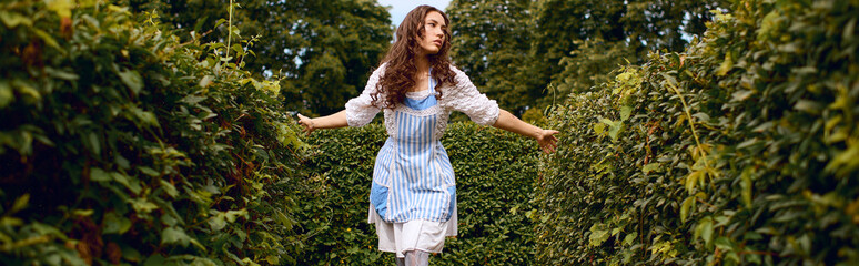 Fototapeta premium Beautiful young woman explores a lush garden in enchanting wonderland style