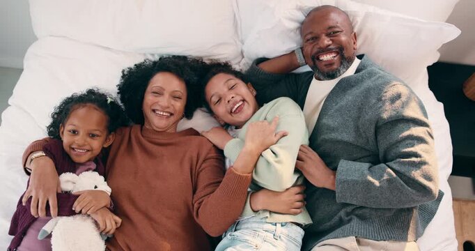 Laughing, above and face of family in bedroom for bonding, support and weekend break. Happiness, connection and love with parents and children lying in bed home for trust, relax and funny joke