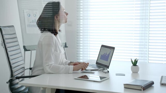 Professional woman crunching numbers and analyzing financial data on a laptop in a bright modern office, planning business strategies and managing growth