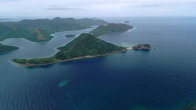 Aerial view of Coron island chain in Palawan Philippines with coral reefs sandy beaches blue ocean green hills cloudy sky and tropical archipelago coastline