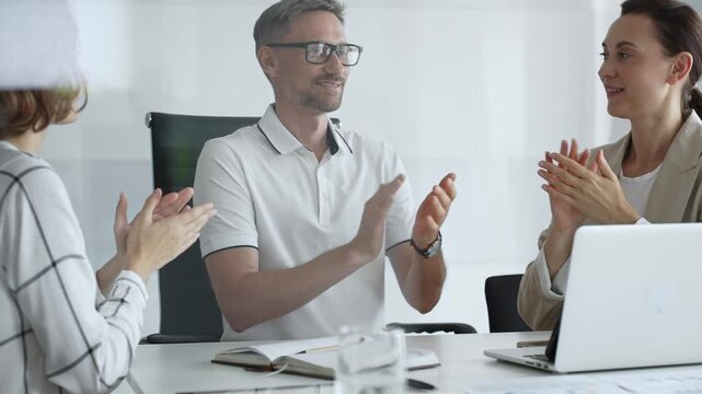 Professional team applauding, celebrating collaborative success and recognizing outstanding performance during corporate meeting, expressing shared workplace achievement