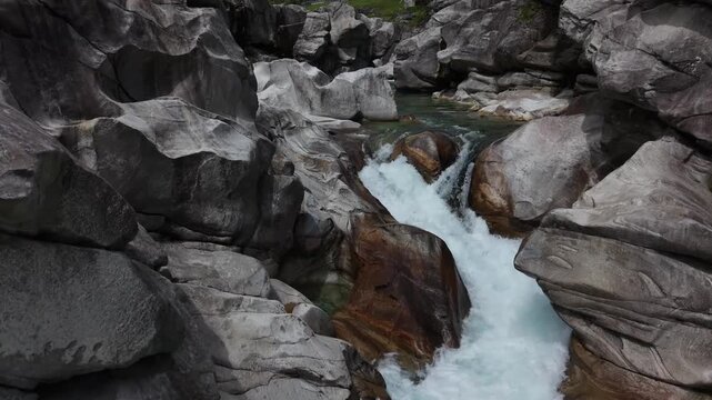 Aerial view of the turquoise Verzasca River flowing through smooth grey boulders in the Valle Verzasca gorge Verzasca, Ticino, Switzerland.
