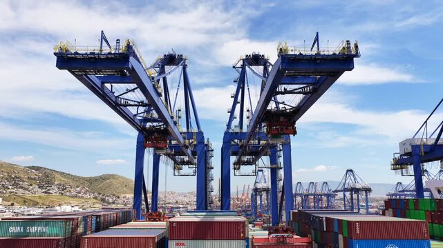 Aerial drone cinematic video during huge cranes loading - unloading truck size merchandize container from ship anchored in port terminal