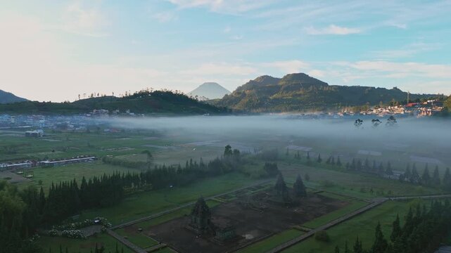 Aerial view of Arjuna Temple complex in Dieng Plateau with morning mist and mountains Kejajar, Central Java, Indonesia.