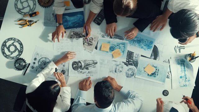 Top down view of skilled engineer showing and talking about turbine engine design. Aerial view of skilled designer or technician group explain about electronic generator construction. Alimentation.