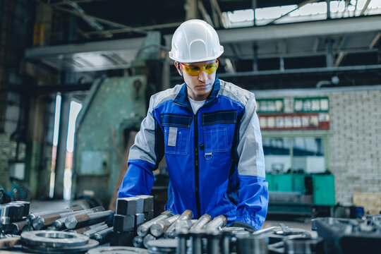 Industrial worker turner inspecting machinery in factory workshop