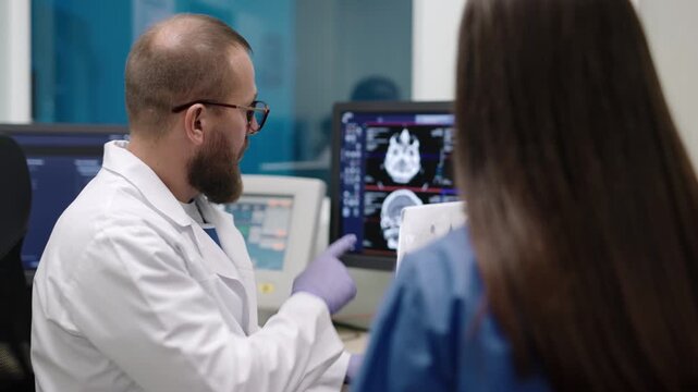 Medical professionals examine MRI brain image on computer monitor, concept of neurology, radiology diagnosis and hospital data analysis.