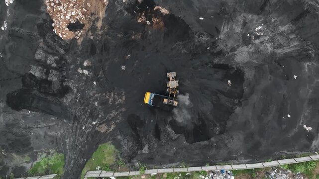 Front loader pouring coal into a dump truck aerial view