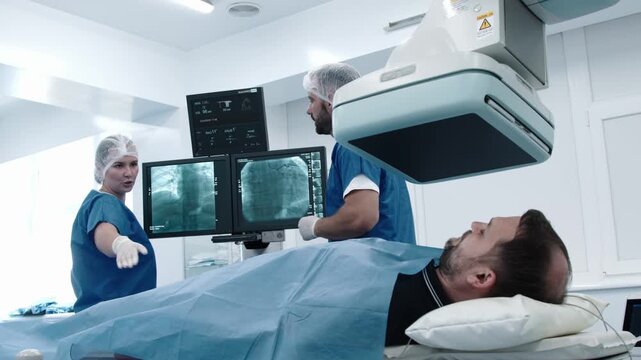 Medical team preparing patient for angiography or CT/MRI scan in hospital imaging department. Concept diagnostic technology, teamwork and modern healthcare.
