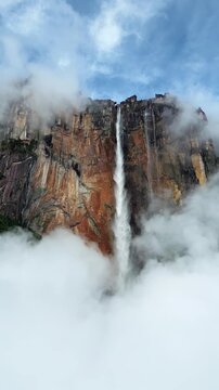 Stunning cinematic drone footage of angel falls in Venezuela plunging from Auyantepui tepui mountain into tropical rainforest clouds.