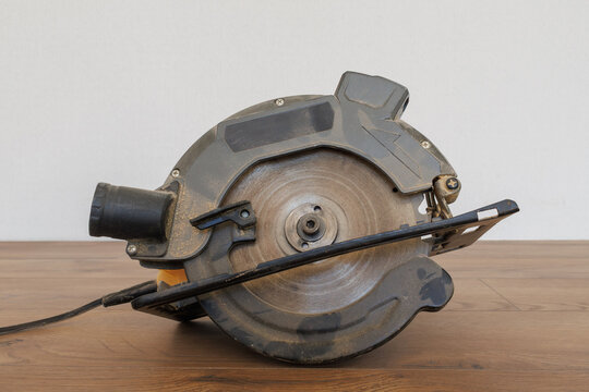 Profile view of a circular saw showing the blade guard and dust extraction port on dark wood