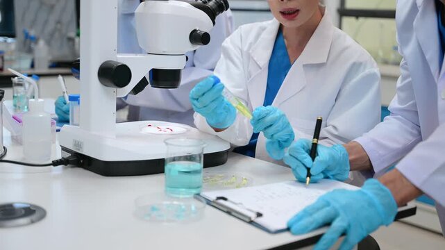 Young scientists conducting research investigations in a medical laboratory, a researcher in the foreground is using a microscope in laboratory for medicine.