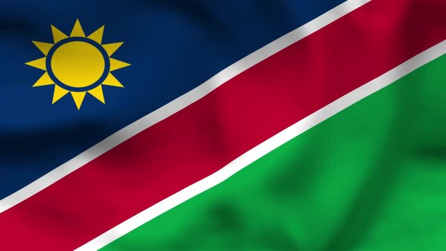 National flag of Namibia on wavy cloth. Features blue and green triangles divided by a red diagonal stripe and a yellow sun. Top-down view for African travel and national holidays.