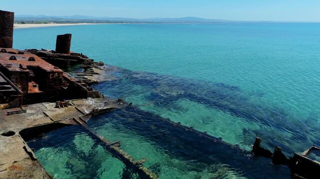 Aerial view of the rusty Shipwreck Epanomi resting in crystal clear turquoise waters under a bright blue sky in Epanomi, Greece.