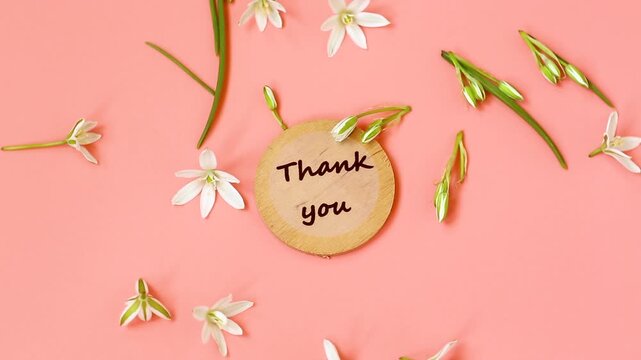 Elegant thank you composition with delicate flowers and pink surface