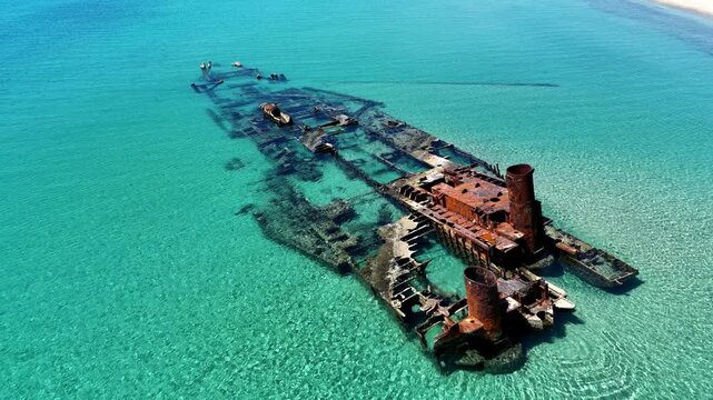 Aerial view of the rusted Shipwreck Epanomi submerged in crystal clear turquoise waters near a sandy beach in Epanomi, Greece.