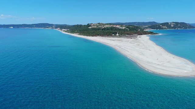 Aerial view of the white sand spit of Possidi Beach surrounded by turquoise waters and green hills in Greece.